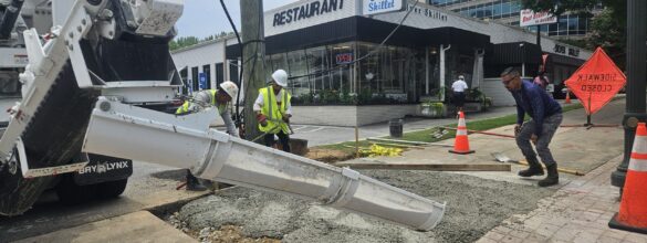 Workers pouring fresh concrete from the Mobile Mixer onto a sidewalk in front of the Silver Skillet restaurant Atlanta